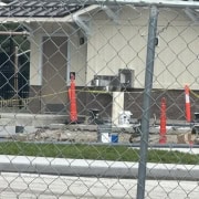 Fostoria News Construction site behind a chain-link fence with orange cones and building materials.